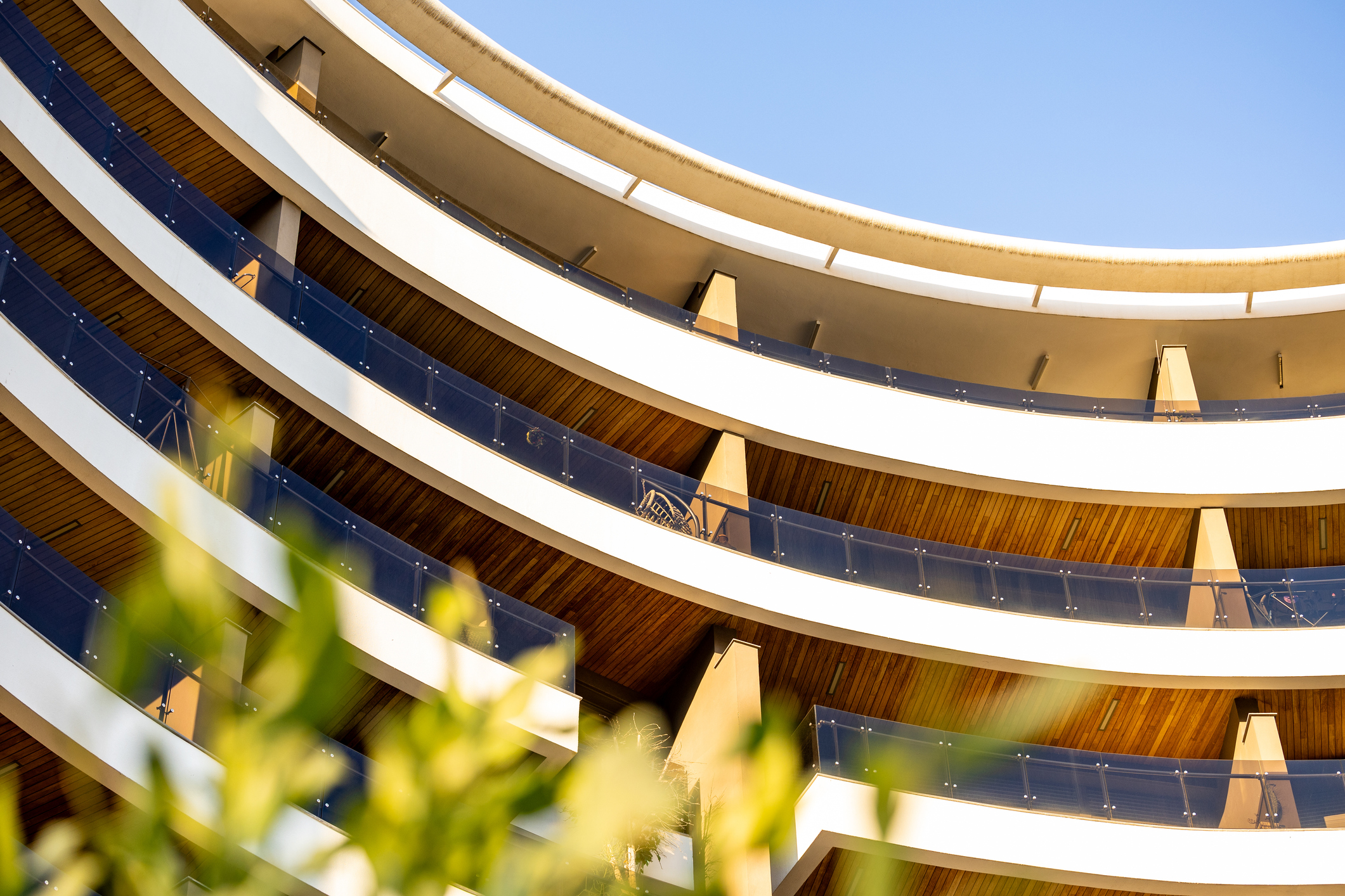 Curved building with balconies and greenery.
