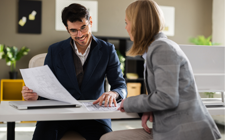 Two professionals discussing architectural plans indoors.