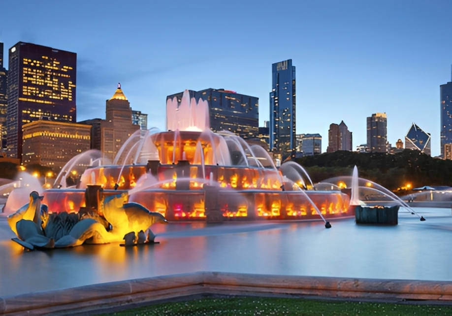 Chicago skyline with illuminated fountain at dusk.